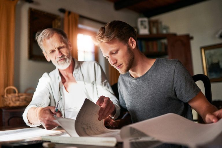 Father taking stewardship over and working with his college-aged son in their family business